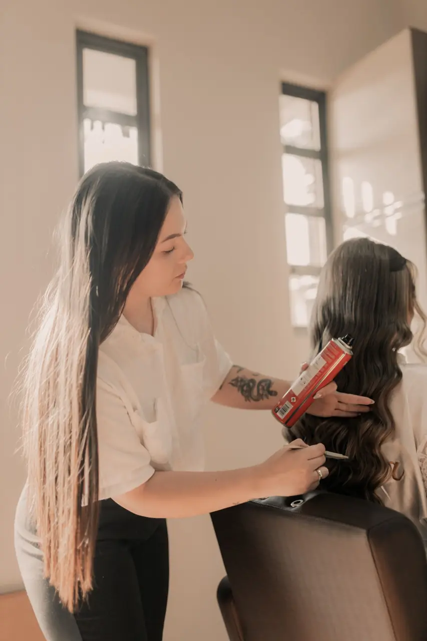 Stylist curling a client's long hair
